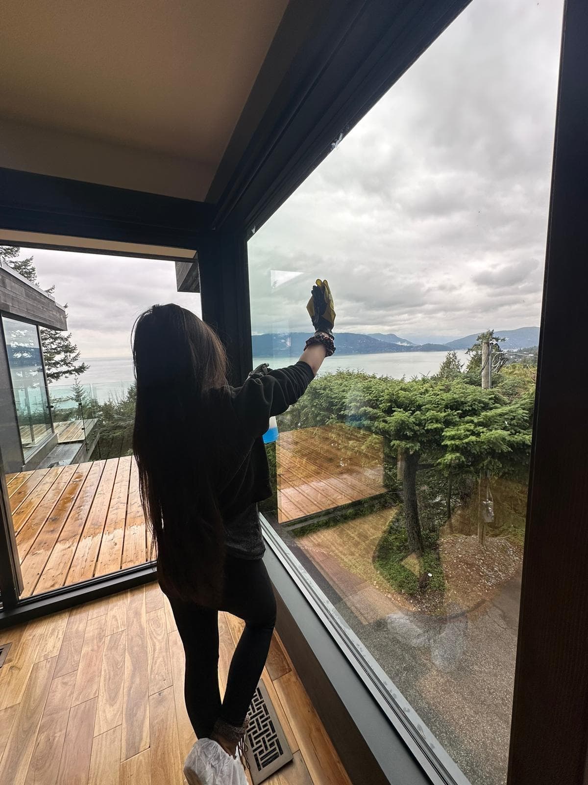 An S&A cleaner cleaning a window with a view