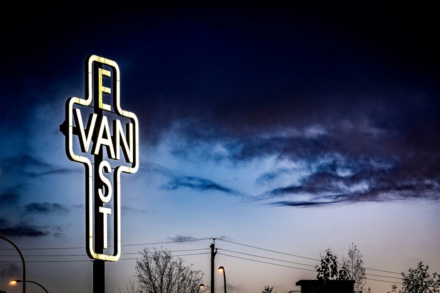 The East Van cross sign lit up at dusk
